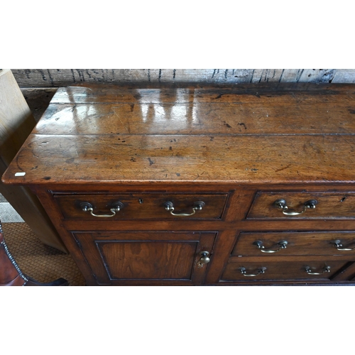 854 - An 18th century oak low dresser, the three plank top over an arrangement of five drawers and two cup... 