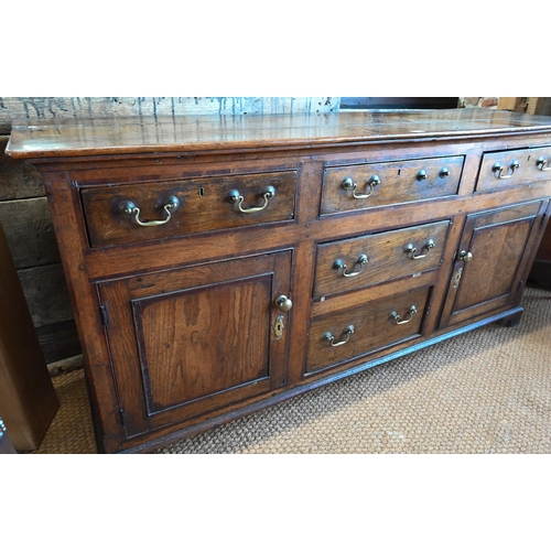 854 - An 18th century oak low dresser, the three plank top over an arrangement of five drawers and two cup... 