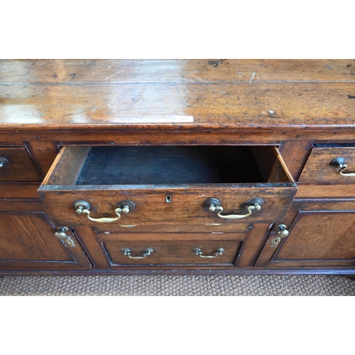 854 - An 18th century oak low dresser, the three plank top over an arrangement of five drawers and two cup... 