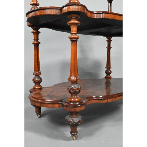 865 - A Victorian figured walnut three-tier whatnot, of all-round serpentine form, raised on brass castors... 