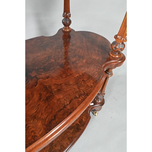 865 - A Victorian figured walnut three-tier whatnot, of all-round serpentine form, raised on brass castors... 