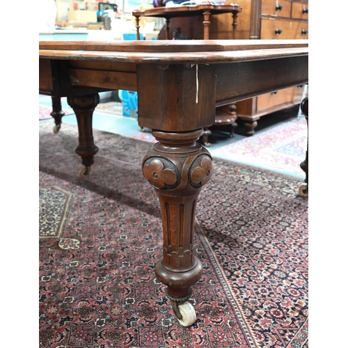 869 - A large Victorian golden oak extending table, the wind action top with rounded corners accepting the... 