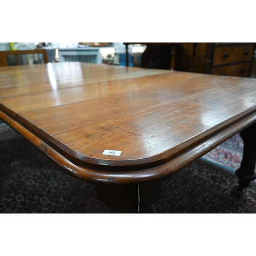 869 - A large Victorian golden oak extending table, the wind action top with rounded corners accepting the... 