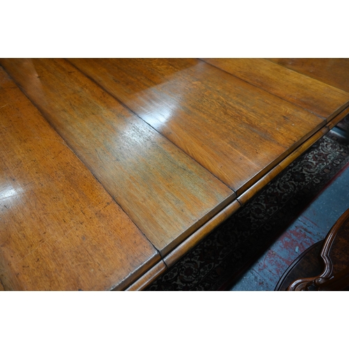 869 - A large Victorian golden oak extending table, the wind action top with rounded corners accepting the... 