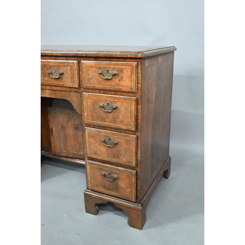 870 - A Georgian style feather-banded walnut kneehole desk, with an arrangement of nine drawers around a r... 