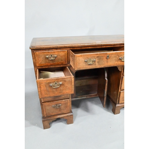 870 - A Georgian style feather-banded walnut kneehole desk, with an arrangement of nine drawers around a r... 