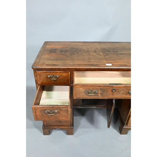 870 - A Georgian style feather-banded walnut kneehole desk, with an arrangement of nine drawers around a r... 