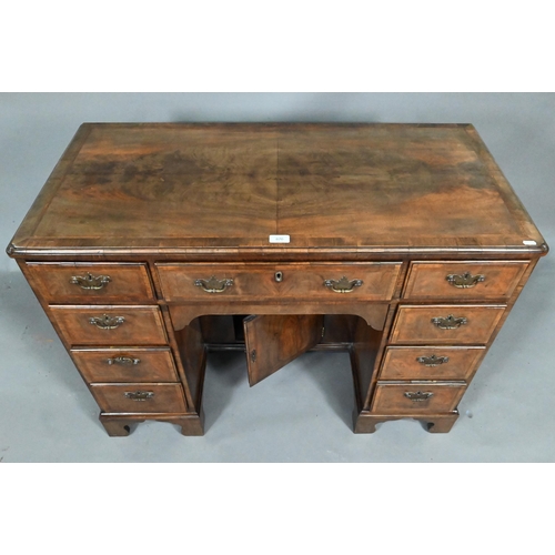 870 - A Georgian style feather-banded walnut kneehole desk, with an arrangement of nine drawers around a r... 