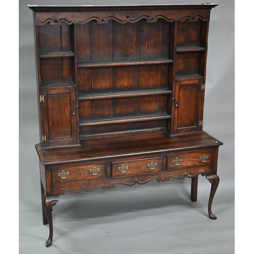 889 - An 18th century style oak high dresser, the rack with dentil moulted canopy centred by open shelves ... 