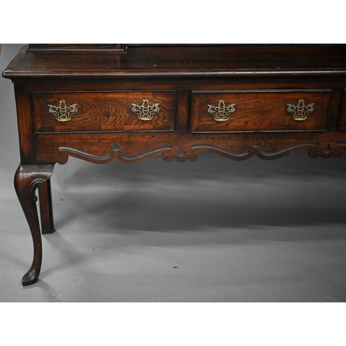 889 - An 18th century style oak high dresser, the rack with dentil moulted canopy centred by open shelves ... 