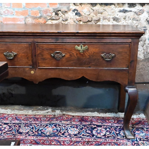 914 - An 18th century cross-banded oak low dresser, with three cock-beaded frieze drawers over a wavy apro... 