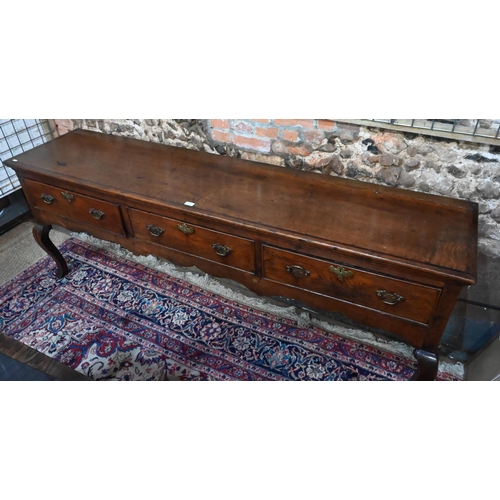 914 - An 18th century cross-banded oak low dresser, with three cock-beaded frieze drawers over a wavy apro... 