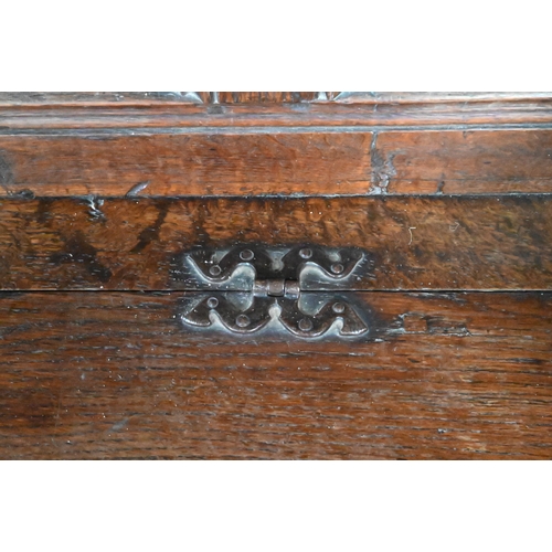 925 - An antique oak box settle, the panelled back with floral carved rosette's over shaped arms and an ir... 