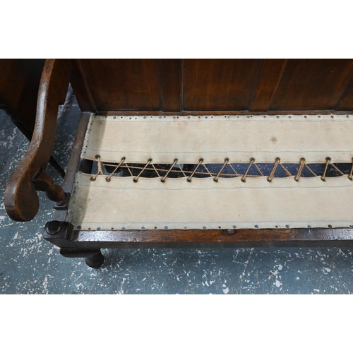 926 - An 18th century oak panel backed settle, with shaped arms over a rope and canvas seat (cushion inclu... 