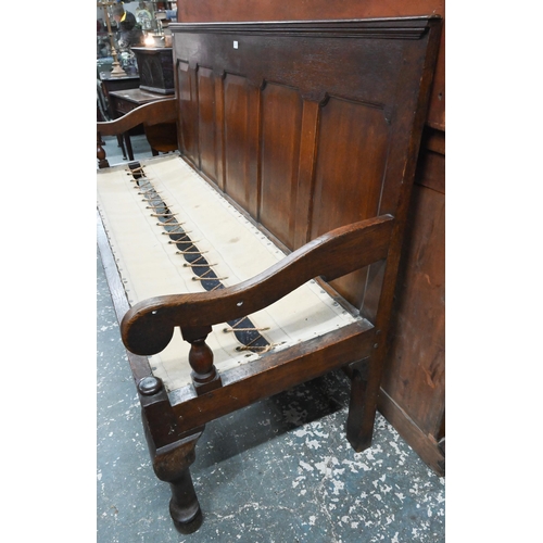 926 - An 18th century oak panel backed settle, with shaped arms over a rope and canvas seat (cushion inclu... 