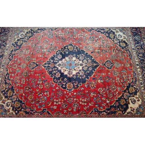 842 - An Indo-Persian Kashan carpet, the red ground centred with a blue ground floral medallion