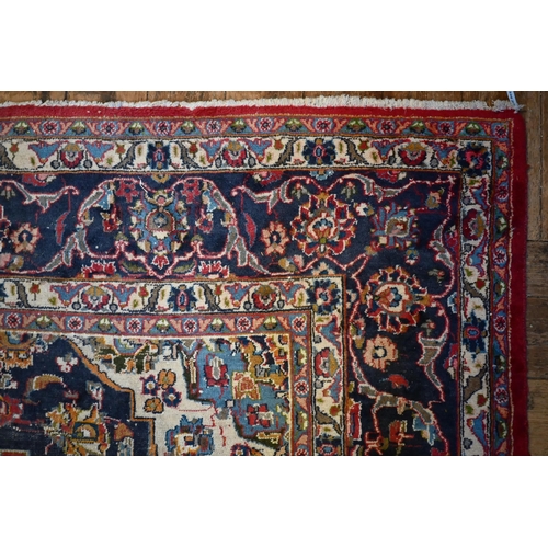 842 - An Indo-Persian Kashan carpet, the red ground centred with a blue ground floral medallion