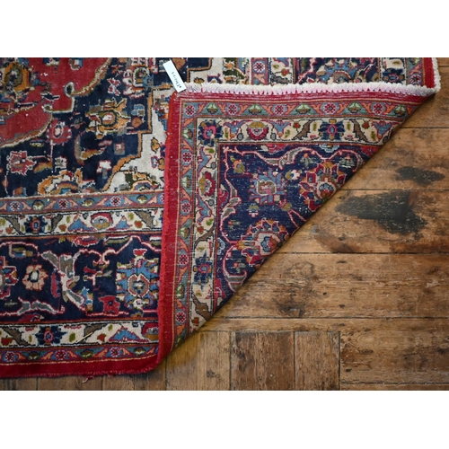 842 - An Indo-Persian Kashan carpet, the red ground centred with a blue ground floral medallion