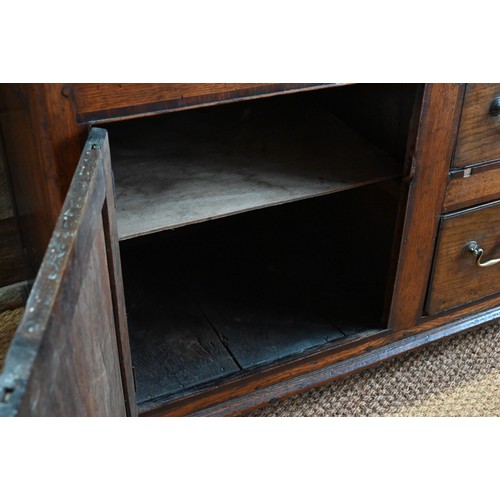 854 - An 18th century oak low dresser, the three plank top over an arrangement of five drawers and two cup... 