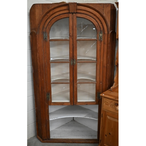 375 - An antique stained pine floor standing corner cabinet with arched glazed doors enclosing two shelves... 