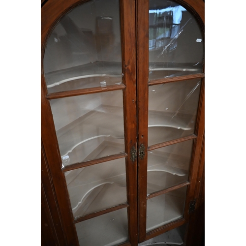 375 - An antique stained pine floor standing corner cabinet with arched glazed doors enclosing two shelves... 