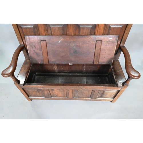 250 - An antique oak box settle, the panelled back with floral carved rosette's over shaped arms and an ir... 