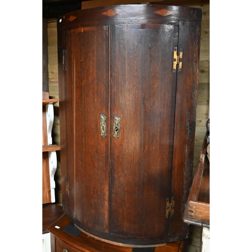 24 - An antique crossbanded oak bow front hanging corner cupboard