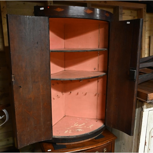 24 - An antique crossbanded oak bow front hanging corner cupboard