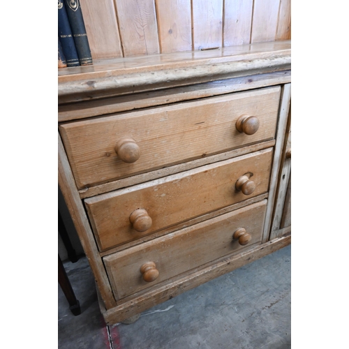 387 - A stripped pine kitchen dresser with two-shelf plate rack on a base with three drawers and panelled ... 