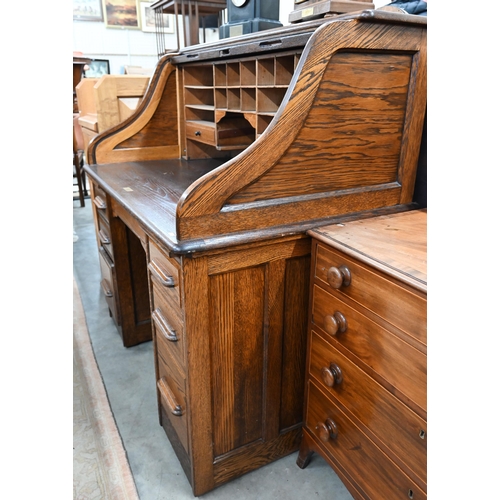 407 - An early 20th century oak roll-top desk, the sliding tambour panel enclosing a fitted interior, over... 