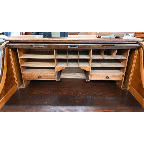 407 - An early 20th century oak roll-top desk, the sliding tambour panel enclosing a fitted interior, over... 