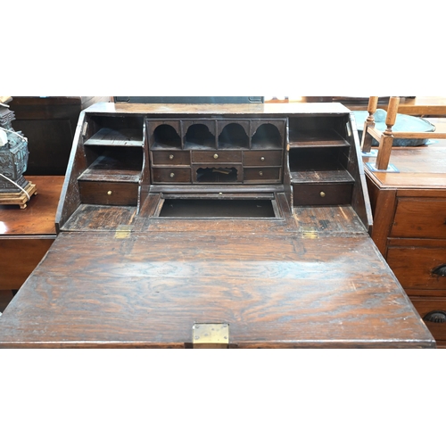 421 - An antique oak fall front bureau with fitted interior and six drawers standing on bun feet 94 cm w x... 