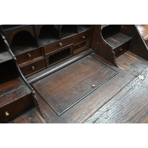 421 - An antique oak fall front bureau with fitted interior and six drawers standing on bun feet 94 cm w x... 