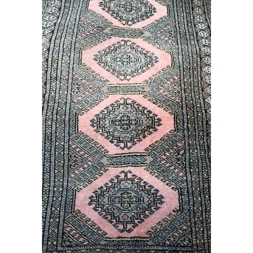 45 - A Teke Bokhara geometric design pink ground rug 131 cm x 78 cm to/with a pair of Turkoman style red ... 