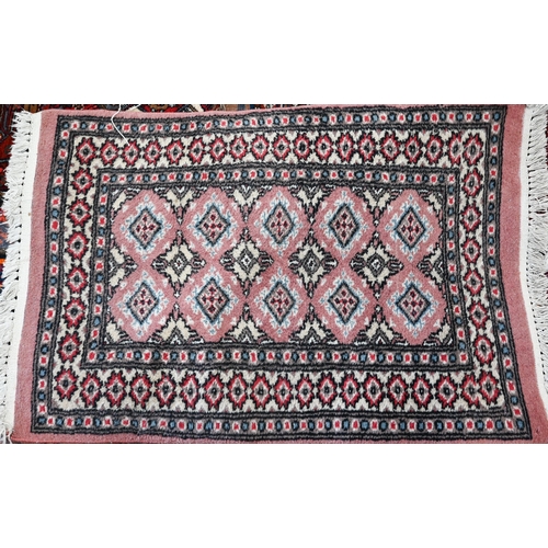 45 - A Teke Bokhara geometric design pink ground rug 131 cm x 78 cm to/with a pair of Turkoman style red ... 