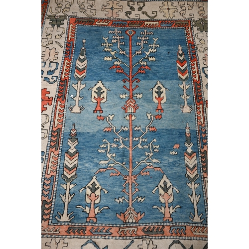 498 - A Turkish Milas rug, abrashed sky-blue ground with symmetrical tree design with geometric cream bord... 