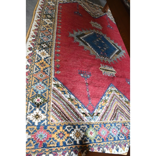 499 - Turkish carpet geometric design with blue diamond medallion on red ground, cream and mustard repeati... 