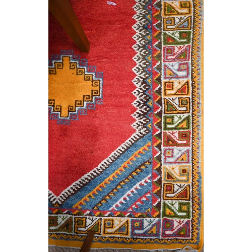 547 - A Moroccan carpet, geometric design on red ground repeating colourful borders, 240 x 160 cm