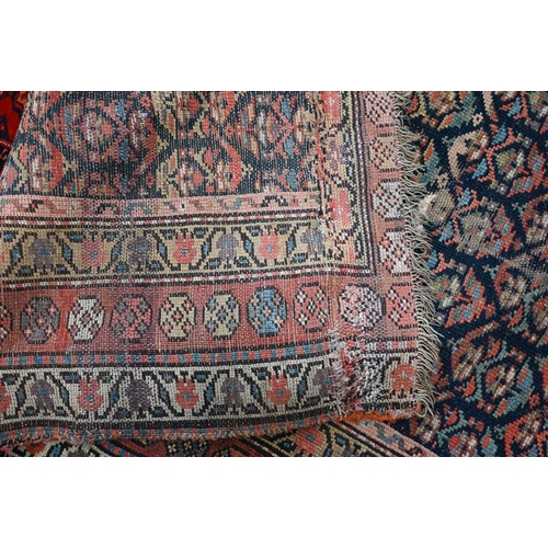 563 - A worn antique Kurdish rug, repeating stylised floral motif on dark blue ground, rosette borders, a/... 