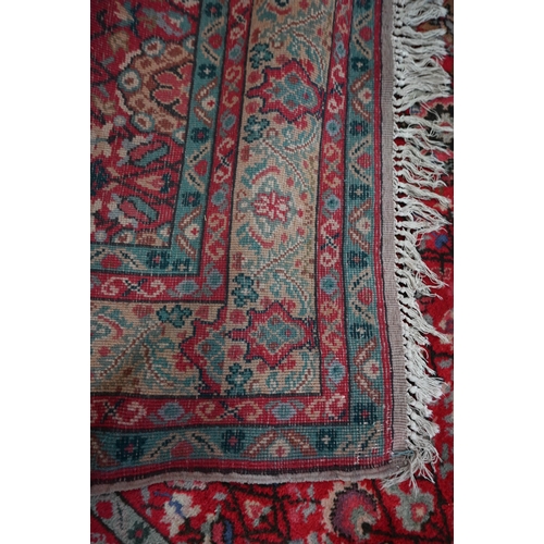 568 - A small Persian carpet, arrangemtn of rosettes and palmettes on ruby red ground, floral cream border... 