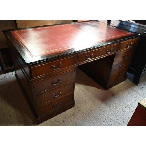 604 - A large twin pedestal mahogany desk with red leather top over an arrangement of nine drawers, on sha... 