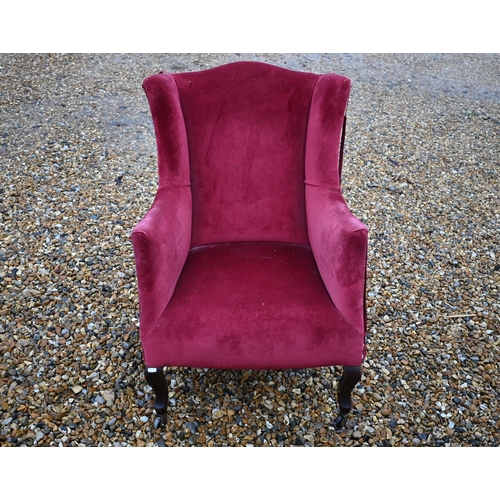 621 - An Edwardian wingback armchair in burgundy dralon upholstery (A/F)