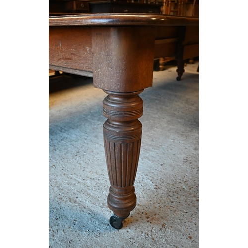 10 - A Victorian oak extending (wind action) dining table, the moulded edge with two leaves (slightly war... 