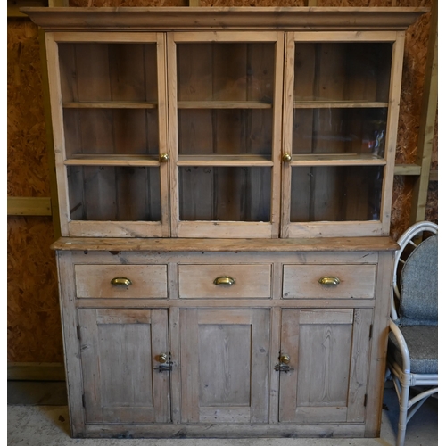 17 - An old pine part glazed dresser, the upper part with three glazed cabinets over three drawers over c... 