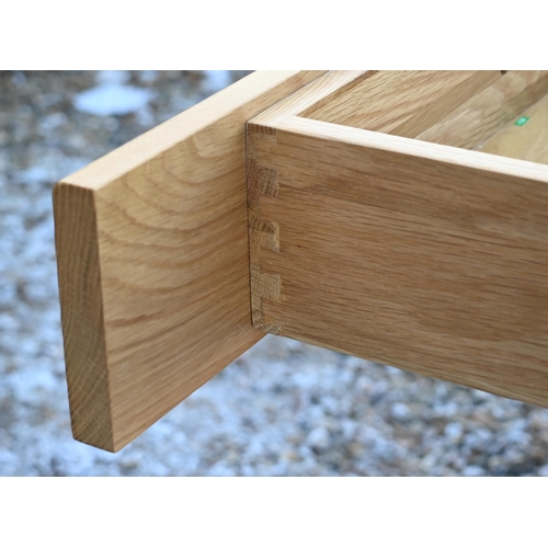 19 - A modern blonde oak two drawer side table/desk, 130 x 55 x 79 cm high to/w a matching single drawer ... 