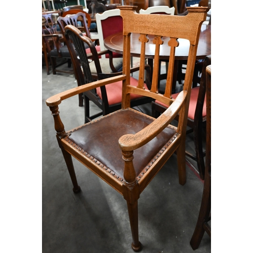 An Arts & Crafts oak elbow chair with studded brown leather padded seat, in the manner of Liberty