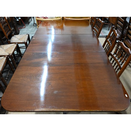 558 - A mahogany twin pedestal extending dining table with two central leaves, on pair of turned column an... 