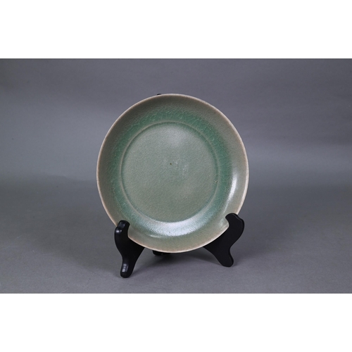 503 - A Chinese celadon dish with combed exterior, covered in a crackled olive green glaze thinning in col... 