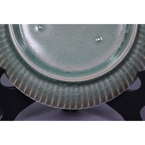 503 - A Chinese celadon dish with combed exterior, covered in a crackled olive green glaze thinning in col... 