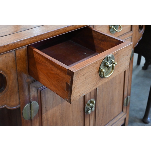 253 - A Chinese hardwood brass mounted altar-top side cabinet with two drawers over panelled cupboard door... 